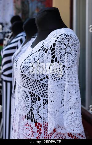 Hauts en dentelle décorés blancs sur des poupées de mode noires devant une vitrine Banque D'Images