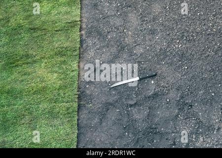 Un long couteau à lame repose sur le sol près d'un gazon nouvellement posé dans un petit jardin au Royaume-Uni Banque D'Images