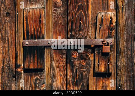 Vieux cadenas rouillé corrodé sur la porte de grange de ferme en bois comme arrière-plan Banque D'Images