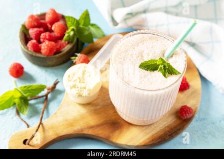 Shake protéiné avec des baies fraîches. Lait frais, framboises boivent sur une planche de bois sur un fond de pierre. Banque D'Images