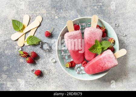 Popsicles de framboise maison avec yaourt et framboises sur un fond de pierre grise. Crème glacée. Dessert d'été. Vue d'en haut. Banque D'Images