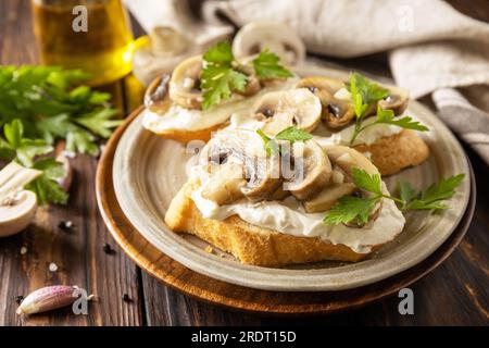 Sandwich grillé de pain baguettes avec fromage à pâte molle et champignons grillés sur la table rustique en bois. Bruschetta maison aux champignons. Banque D'Images