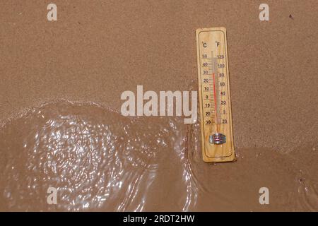 Thermomètre sur sable sur une plage montrant une température élevée. Concept de temps chaud et de climat Banque D'Images