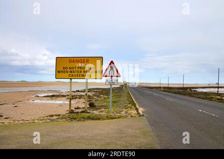 panneaux d'avertissement sur la chaussée à holy island au large de la côte du northumberland Banque D'Images