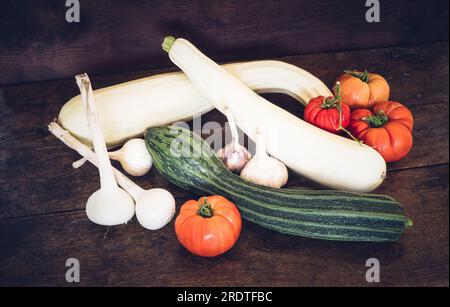 Courgettes, courges, tomates, ail, oignons sur une vieille table en bois Banque D'Images