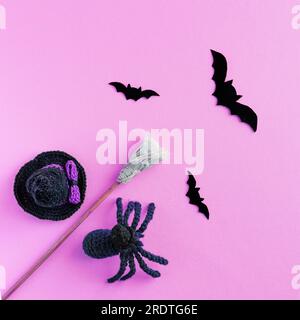 Concept Halloween. Chapeau noir, balai de sorcière et chauves-souris noires et araignée sur fond lilas Banque D'Images