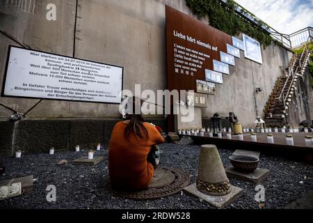 Duisburg, Allemagne. 23 juillet 2023. Une jeune femme est assise par terre au mémorial pour les victimes de la catastrophe de Love Parade. Le 24 juillet 2010, 21 personnes âgées de 17 à 38 ans sont écrasées à la seule entrée et sortie de la technoparade. Au moins 652 visiteurs de Love Parade ont été blessés à ce moment-là. Chaque année, les proches survivants commémorent les victimes. Crédit : Christoph Reichwein/dpa/Alamy Live News Banque D'Images