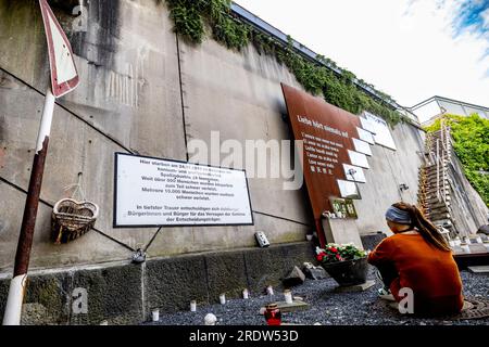 Duisburg, Allemagne. 23 juillet 2023. Une jeune femme est assise par terre au mémorial pour les victimes de la catastrophe de Love Parade. Le 24 juillet 2010, 21 personnes âgées de 17 à 38 ans sont écrasées à la seule entrée et sortie de la technoparade. Au moins 652 visiteurs de Love Parade ont été blessés à ce moment-là. Chaque année, les proches survivants commémorent les victimes. Crédit : Christoph Reichwein/dpa/Alamy Live News Banque D'Images