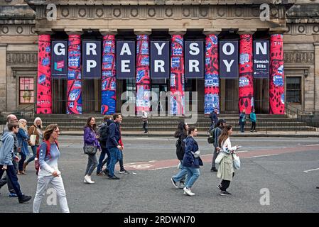 Piétons sur Princes Street se promènent devant la Royal Scottish Academy pour annoncer l'exposition Grayson Perry, qui fait partie du Festival d'Édimbourg 2023. Banque D'Images