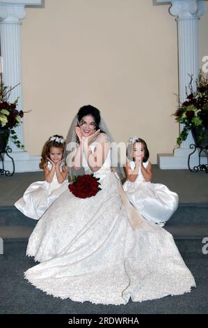 Les filles de mariée et de fleur jouent quelques jeux avant la cérémonie pour créer des photos amusantes. Tous les trois coupent leurs visages et sourient. Banque D'Images