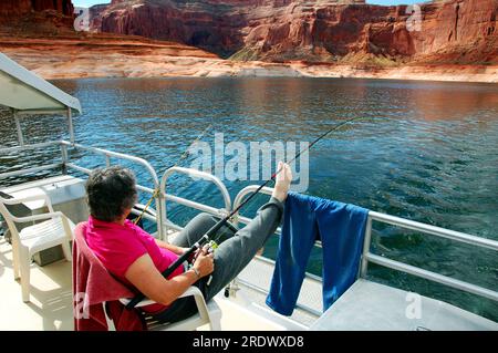 Femme pêche et bénéficie d'une vue depuis une péniche sur le lac Powell. Banque D'Images