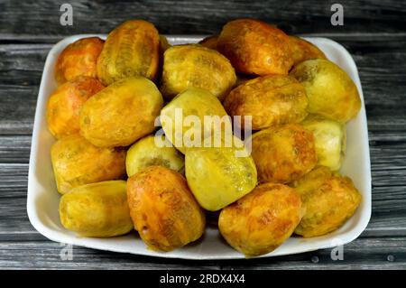 Un tas de fruits de Barbarie frais pelés dans une assiette isolée sur fond en bois, Opuntia, communément appelé poire de Barbarie, fruit de thon, sa Banque D'Images