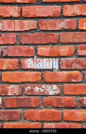 Mortier noir entre les briques rouges décolorantes sur le mur avec la texture émiettante Banque D'Images