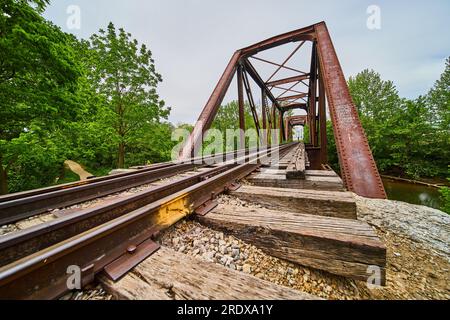 Vue latérale inclinée des voies ferrées avec poutres en bois sous les voies menant au pont ferroviaire Banque D'Images