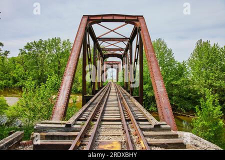 Photo d'été de l'entrée de l'ancien pont de train avec des voies ferrées menant à la ville Banque D'Images