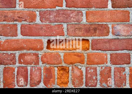 L'actif de fond a émietté des briques rouges sur le mur avec des briques longues et courtes dans des directions variables Banque D'Images