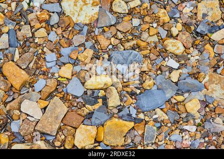 Roches et cailloux de rivière dans l'assortiment coloré sur le sol avec schiste dans l'actif de fond Banque D'Images