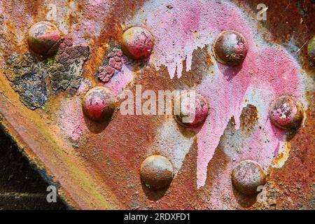 Faisceau industriel abstrait ou corrosion rouillée rouge et orange au bleu et jaune avec des flocons noirs Banque D'Images