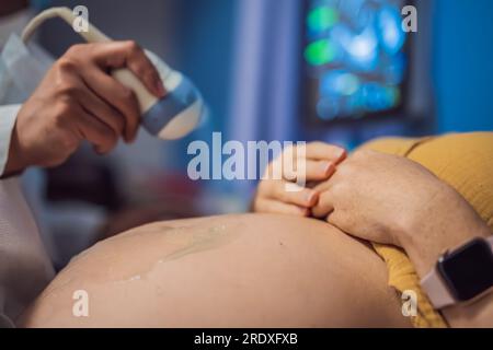 À l'hôpital, la prise de vue rapprochée du médecin effectue une procédure d'échographie à une femme enceinte. Capteur de mouvement obstétricien sur le ventre de Banque D'Images