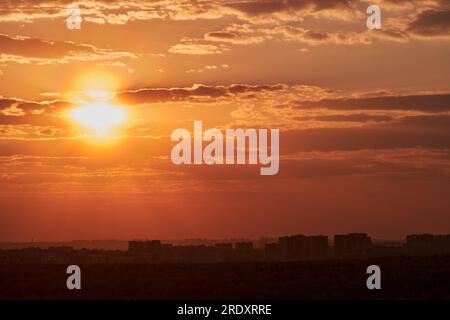 Le soleil couchant projette une lueur chaude sur la ville, tandis que le ciel devient orange et rouge. Banque D'Images