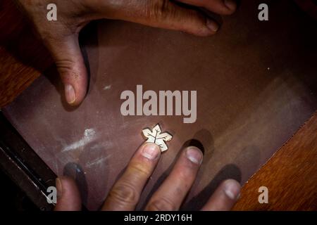 Homme joaillier Goldsmith travaillant dans son atelier de fabrication de bijoux créant et broyant un bijou en or blanc ou en argent dans son atelier de travail. Banque D'Images