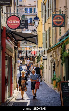 Antibes, France - 24 mai 2023 : les gens marchent entre les magasins dans les vieilles maisons dans une rue près du marché provençal couvert local dans la vieille ville Banque D'Images