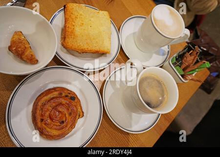 Café noir chaud Americano et Cappuccino servi avec croque monsieur, mini croissant et petit pain danois Banque D'Images