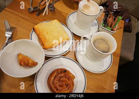 Café noir chaud Americano et Cappuccino servi avec croque monsieur, mini croissant et petit pain danois Banque D'Images