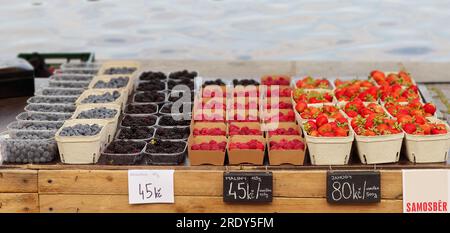 Bols en papier et en plastique remplis de fraises fraîches, bleuets, framboises et mûres prêts pour les clients au stand de rue chez les agriculteurs f Banque D'Images