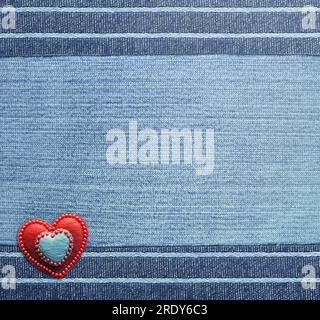 Fond de denim bleu avec des bordures rayées et coeur en feutre rouge. Texture du tissu Jean denim couleur marine. Toile de fond denim Saint-Valentin. Copier l'espace pour t Banque D'Images