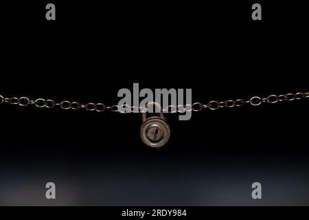 Vieux cadenas sur une chaîne pèse sur un fond noir gros plan Banque D'Images