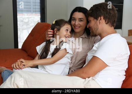 Femme souriante avec la famille assise sur le canapé à la maison Banque D'Images