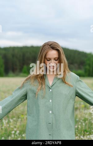 Jeune femme en chemise verte debout avec les bras tendus sur le terrain Banque D'Images