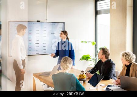 Jeune femme d'affaires en discussion avec des collègues en réunion Banque D'Images