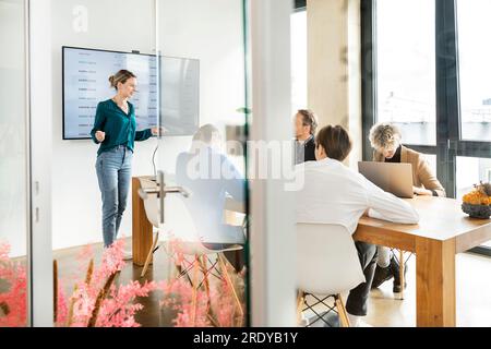 Femme d'affaires donnant la présentation avec des collègues dans le bureau Banque D'Images