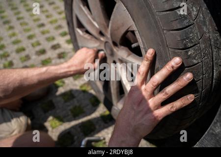 Mains de l'homme changeant le pneu de voiture dans la cour Banque D'Images