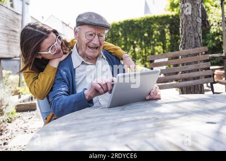 Fille avec grand-père utilisant tablette PC à table Banque D'Images