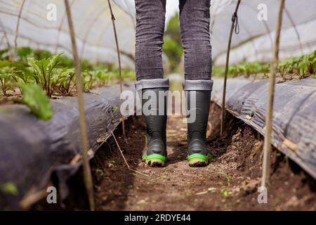 Jeune fermier portant des bottes en caoutchouc debout dans la ferme Banque D'Images