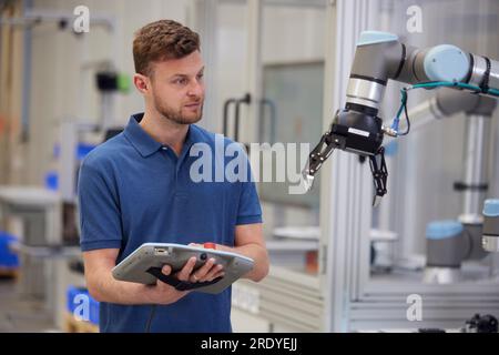 Technicien utilisant un bras robotisé à l'aide d'équipements dans l'industrie Banque D'Images