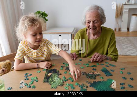 Grand-mère souriante et petite-fille résolvant le puzzle Banque D'Images