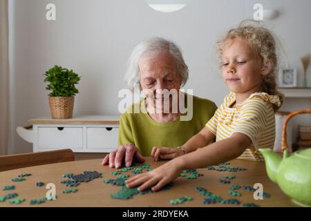 Grand-mère et petite-fille résolvant le puzzle sur la table Banque D'Images