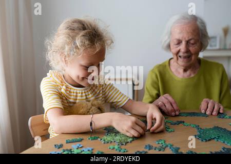 Petite-fille et grand-mère résolvant le puzzle sur la table Banque D'Images