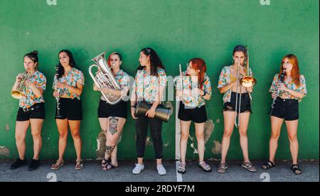 Groupe folklorique de femmes hipster debout avec des instruments de musique devant le mur Banque D'Images