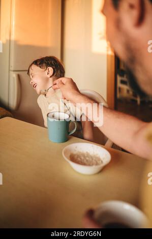 Garçon refusant de manger de la bouillie à la table à manger Banque D'Images