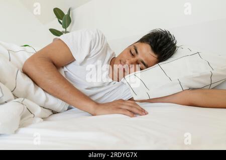 Jeune homme faisant la sieste sur le lit à la maison Banque D'Images