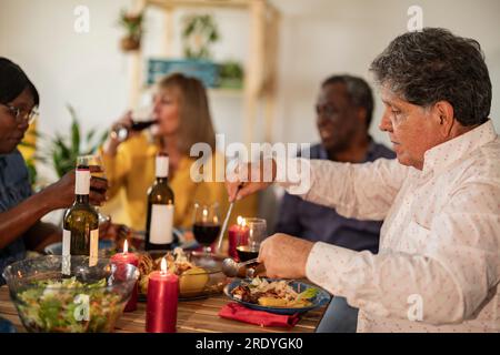 Homme senior mangeant de la nourriture avec des amis au dîner Banque D'Images