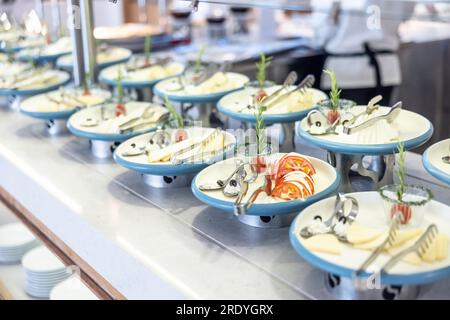 Décorez de manière créative la table du buffet au restaurant de l'hôtel. Tomates avec de la mozzarella et des olives sur une assiette, elle a mené d'autres assiettes de fromage et d'herbes. Banque D'Images