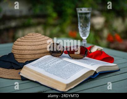 Scène emblématique d'été d'une chaude journée paresseuse d'été - un chapeau de soleil, un livre, une coupe de champagne et des lunettes de soleil Banque D'Images