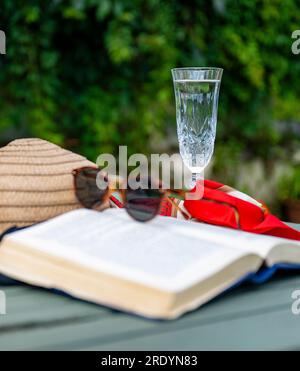 Scène emblématique d'été d'une chaude journée paresseuse d'été - un chapeau de soleil, un livre, une coupe de champagne et des lunettes de soleil Banque D'Images