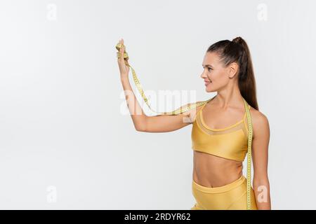 perte de poids, belle sportswoman avec le corps tonique tenant le ruban à mesurer sur fond blanc Banque D'Images